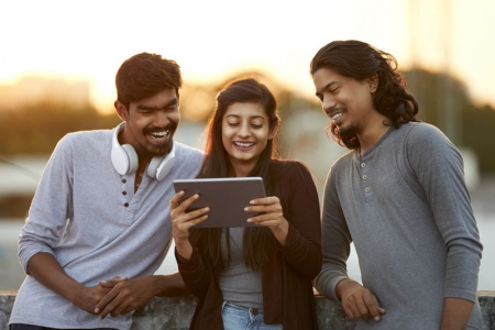 group of young adults looking at an ipad