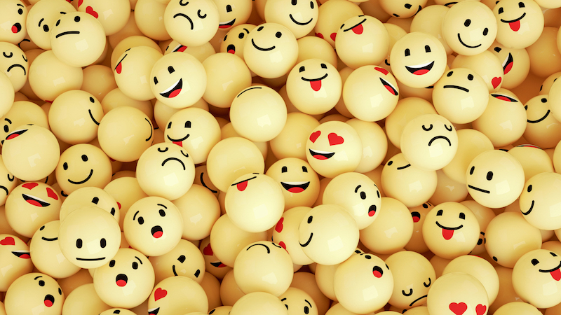Yellow pingpong balls with emoji faces drawn on them.