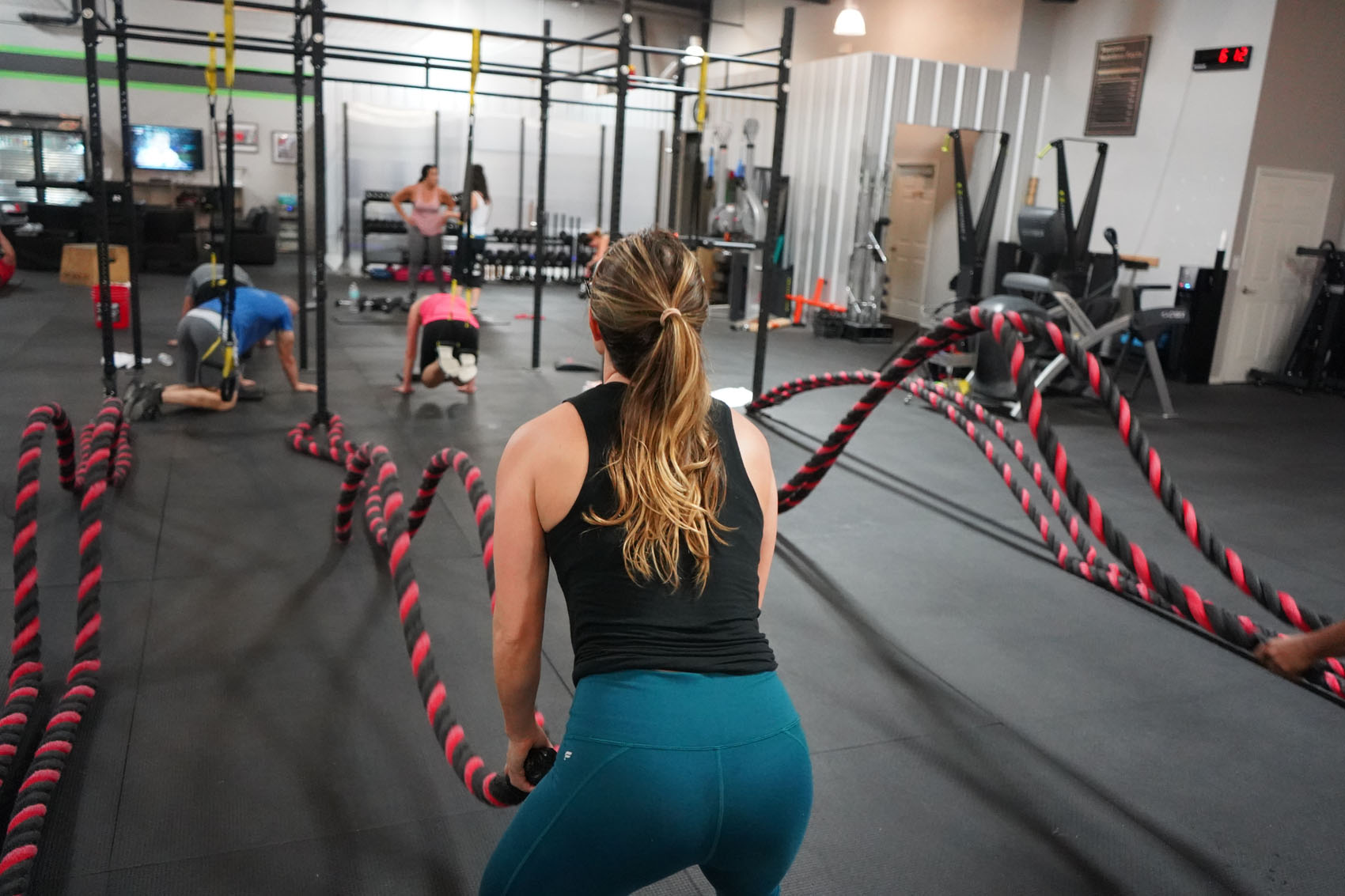 Woman in the gym using battle ropes