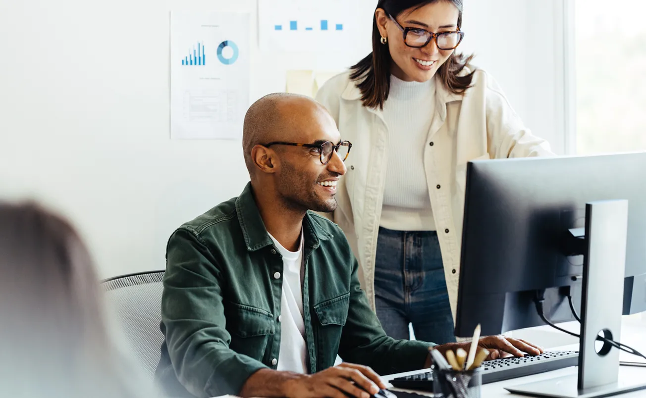 Web developers using a computer together in an office