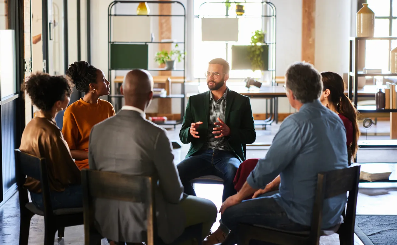 Young businessman talking during a casual office meeting with colleagues