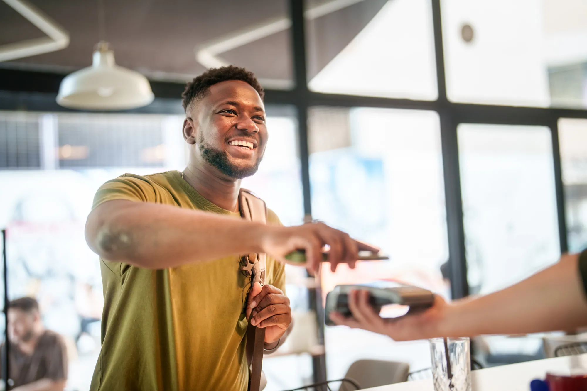 Young student mobile paying in a coffee shop