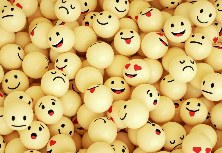 Yellow pingpong balls with emoji faces drawn on them.