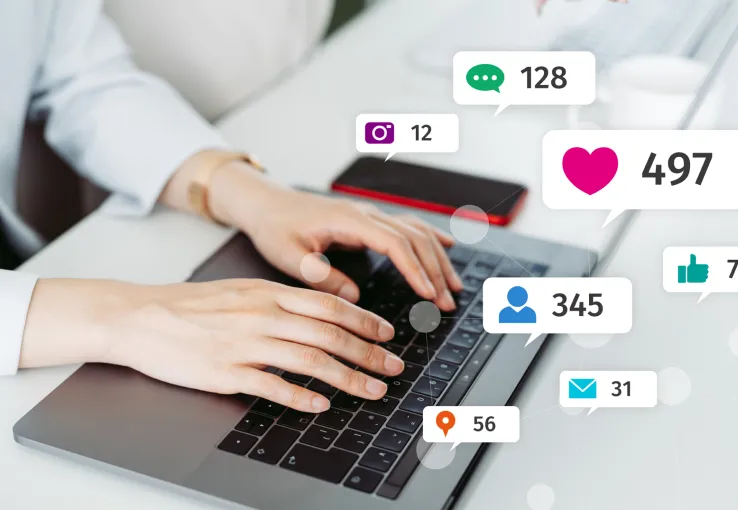 Someone typing on a laptop with illustrations of social media reactions floating through the air to show how researchers can use social media listening for innovation and product development.