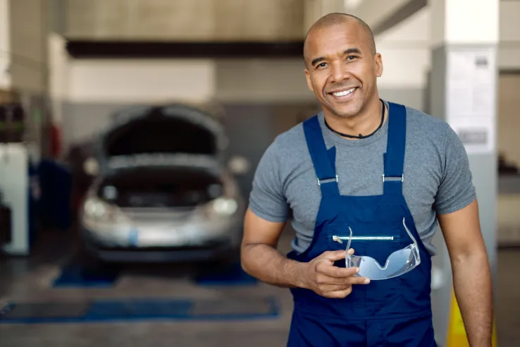 Mechanic smiling in a workshop, representing improved customer satisfaction and business growth