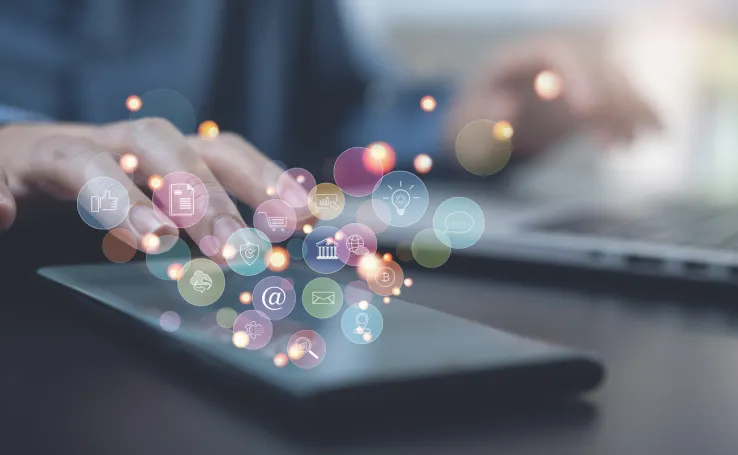 Close-up of hands using a tablet with glowing digital icons (apps, data, and communication symbols) floating above the scree, representing real-time customer data 